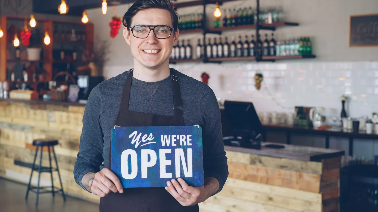 Barista holding an open sign